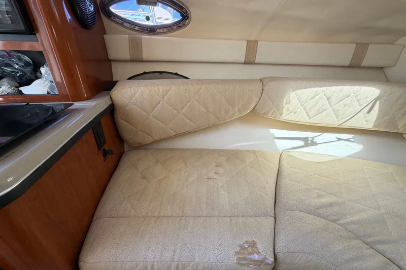 Slide: The Image of Interior cabin of a 2007 Sea Ray 240 Sundancer with beige seating and wood accents. - 58