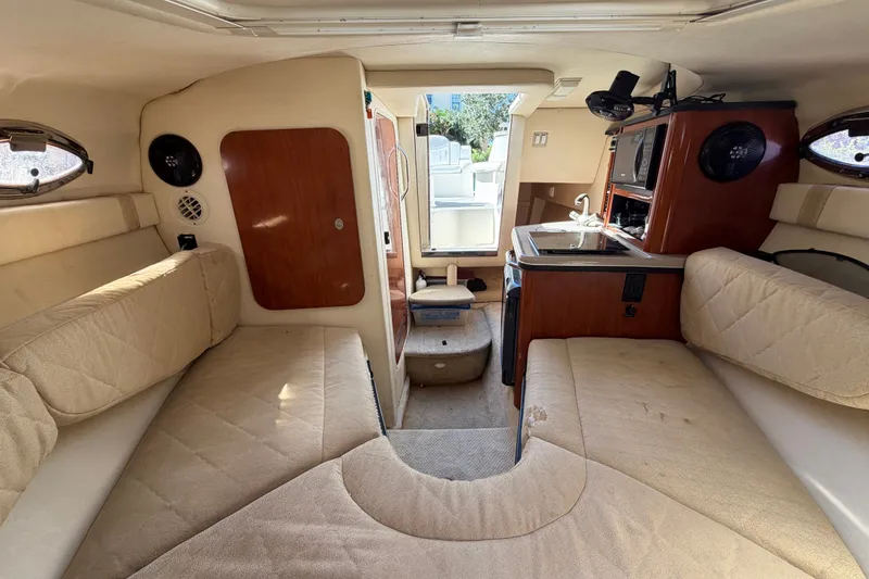 Slide: The Image of Interior of 2007 Sea Ray 240 Sundancer boat with beige seating and compact kitchenette. - 65