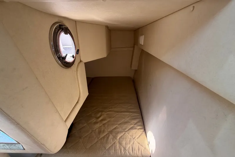 Slide: The Image of 2007 Sea Ray 240 Sundancer cabin interior with porthole and cushioned sleeping area. - 76