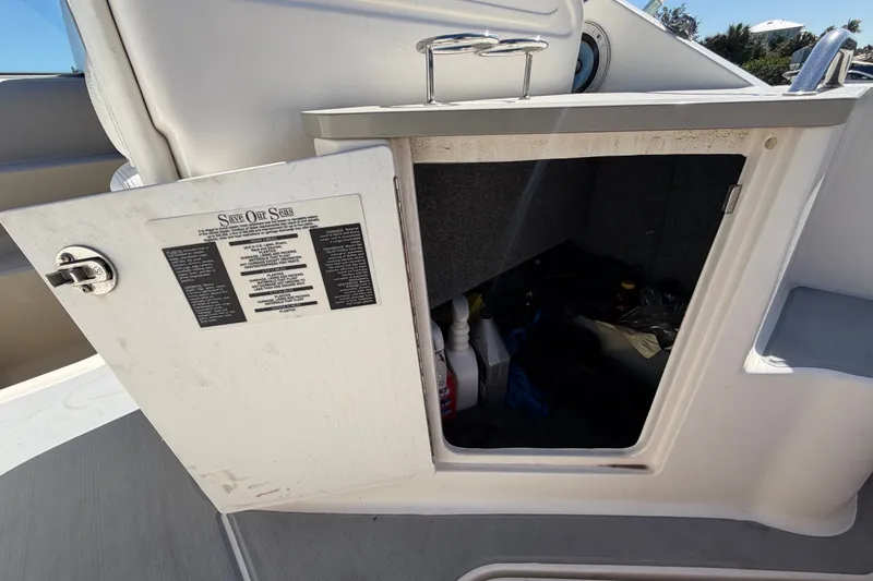 Slide: The Image of Open storage compartment on a 2007 Sea Ray 240 Sundancer boat, containing various items. - 20