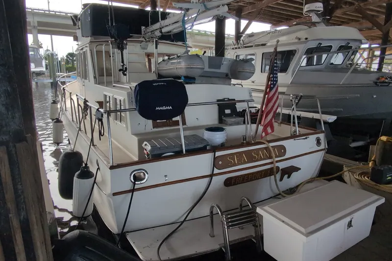 Slide: The Image of 1990 Grand Banks 36 Classic yacht docked, featuring American flag and nautical equipment. - 4