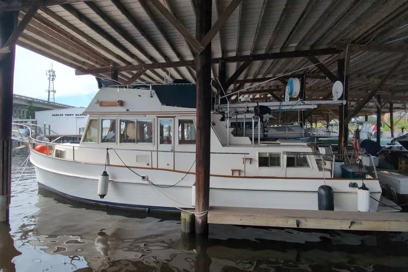 Slide: The Image of 1990 Grand Banks 36 Classic yacht docked at Sadler Point Marina under a covered shelter. - 2