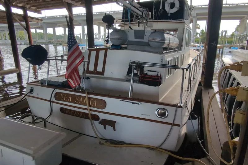 Slide: The Image of 1990 Grand Banks 36 Classic docked under a bridge, displaying an American flag. - 6