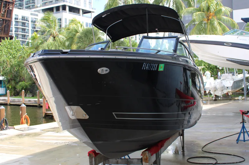 Slide: The Image of 2021 Monterey 255SS Super Sport boat docked, surrounded by tropical trees and modern buildings. - 6