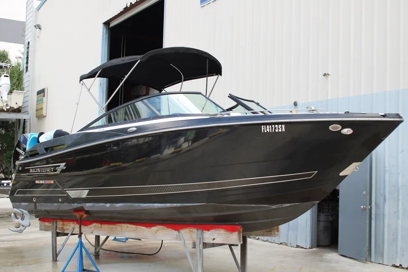 Slide: The Image of 2021 Monterey 255SS Super Sport boat in a marina, black hull, on a lift. - 3