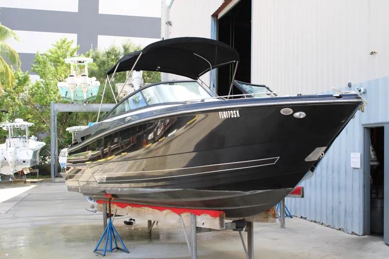 Slide: The Image of 2021 Monterey 255SS Super Sport boat in a marina, black hull, on stands. - 1