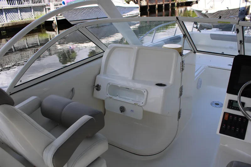 Slide: The Image of 2021 World Cat 255 DC boat interior with seating and helm, docked by water. - 23