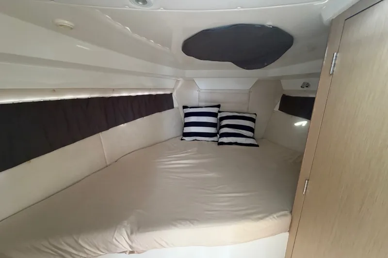 Slide: The Image of Cozy cabin interior of 2024 Sardine Marine 34 with striped pillows and beige bedding. - 32