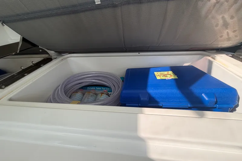 Slide: The Image of Open storage compartment on Sardine Marine 34 boat, featuring hose and blue case, 2024 model. - 15