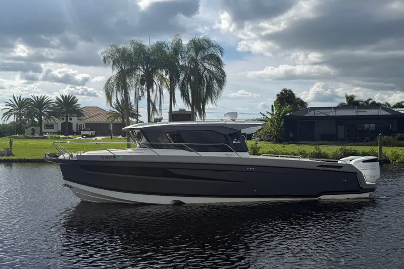 The Image of 2024 Sardine Marine 34 boat on a calm river with palm trees and houses in the background. - 0