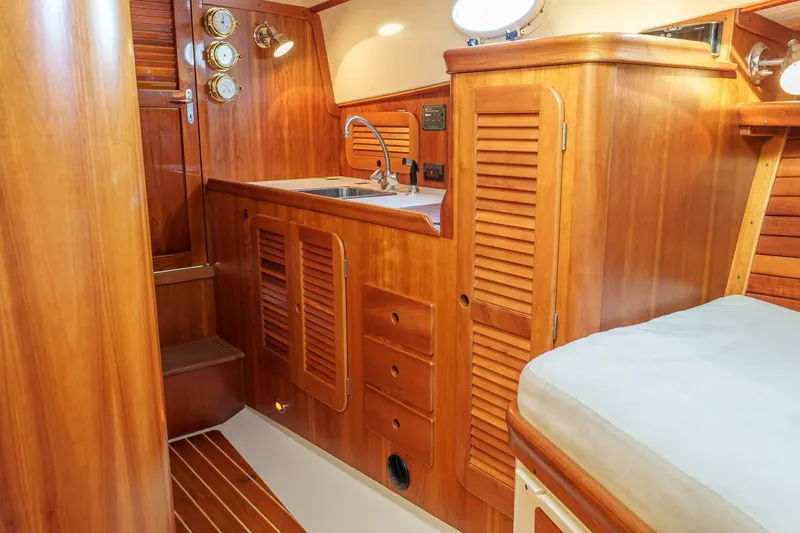 Slide: The Image of Interior of 2001 Hinckley Picnic Boat 36 EP with wooden cabinetry and compact sink area. - 21