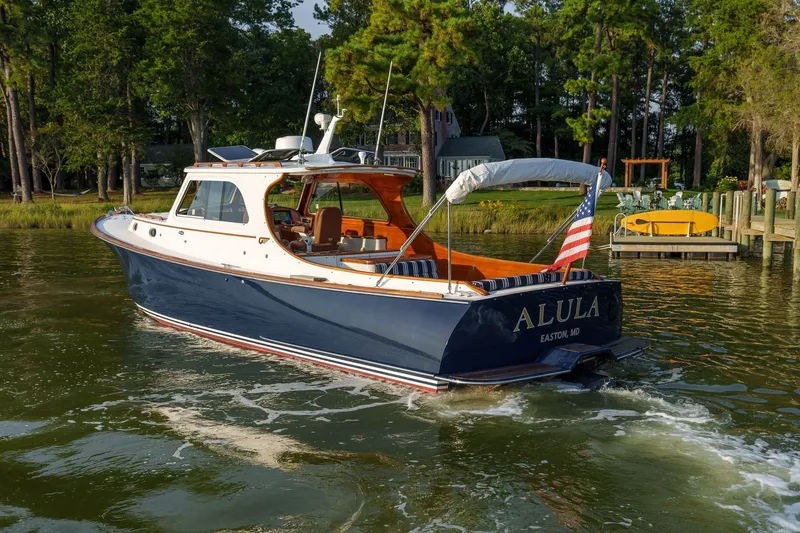 Slide: The Image of 2001 Hinckley Picnic Boat 36 EP cruising on a serene lake with lush greenery. - 26