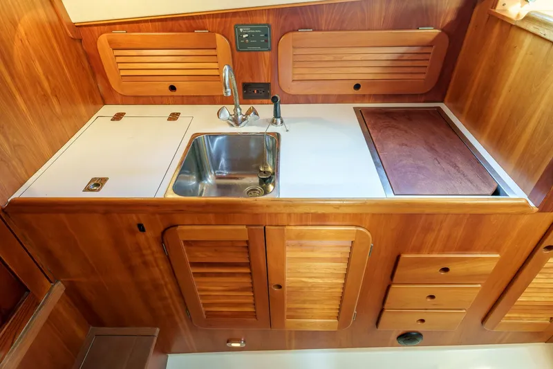 Slide: The Image of 2001 Hinckley Picnic Boat 36 EP galley with wooden cabinetry and stainless steel sink. - 23