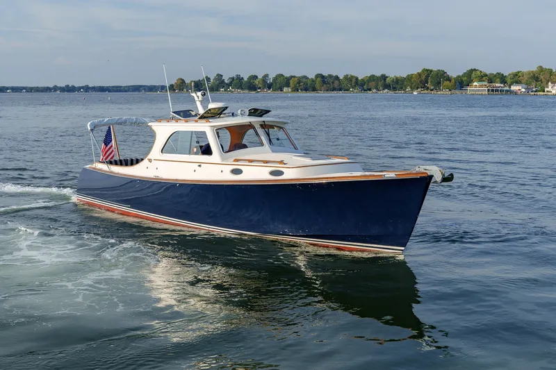 The Image of 2001 Hinckley Picnic Boat 36 EP cruising on a calm lake with scenic shoreline. - 0