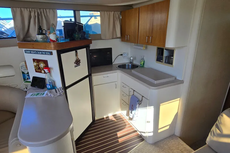 Slide: The Image of 1994 Mainship 40 Sedan Bridge interior kitchen with sink, fridge, and wooden cabinets. - 18