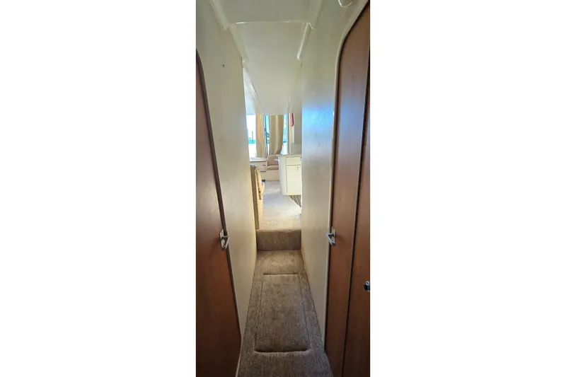 Slide: The Image of Narrow hallway inside 1994 Mainship 40 Sedan Bridge yacht, featuring carpeted flooring and wooden doors. - 32