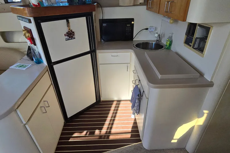 Slide: The Image of 1994 Mainship 40 Sedan Bridge kitchen with fridge, microwave, sink, and wooden flooring. - 21
