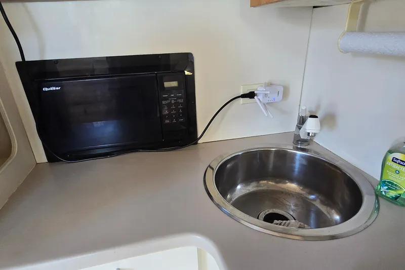 Slide: The Image of Compact kitchen area in a 1994 Mainship 40 Sedan Bridge with microwave and sink. - 23