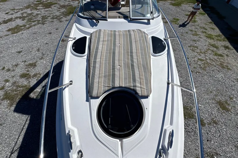 Slide: The Image of 2017 Regal 28 Express boat with striped sun pad on deck, parked on gravel. - 59