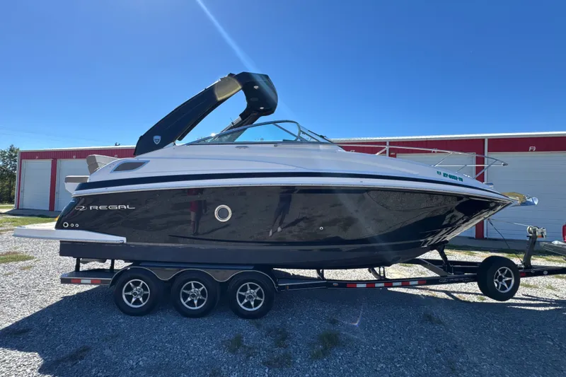 The Image of 2017 Regal 28 Express boat on trailer, parked outdoors under clear blue sky. - 0