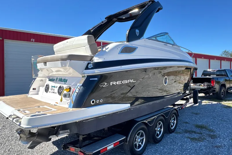 Slide: The Image of 2017 Regal 28 Express boat on trailer, parked outdoors near storage units. - 14