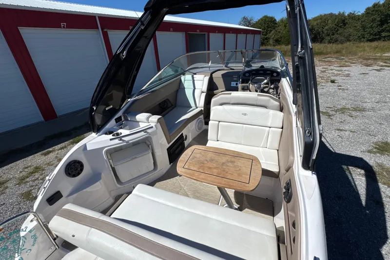 Slide: The Image of 2017 Regal 28 Express boat interior with seating and wooden table, parked outdoors. - 26