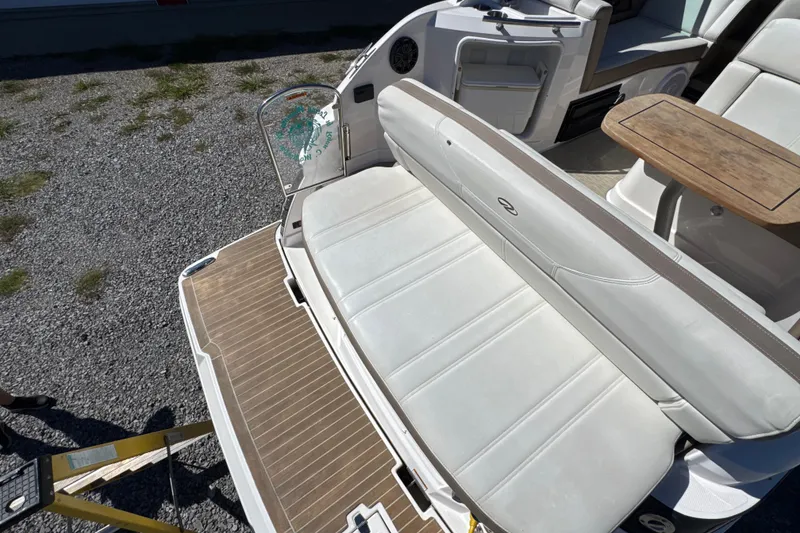 Slide: The Image of 2017 Regal 28 Express boat interior with white seating and wooden table on gravel surface. - 25