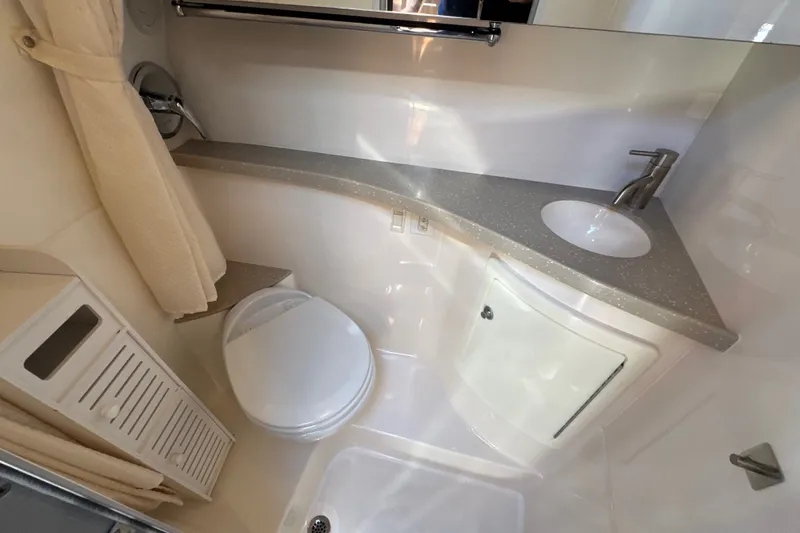 Slide: The Image of Compact bathroom in a 2017 Regal 28 Express boat, featuring a toilet, sink, and storage. - 79