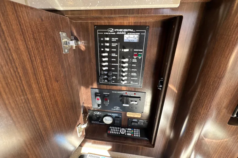 Slide: The Image of Control panel inside 2017 Regal 28 Express boat, featuring switches and gauges on a wooden panel. - 86