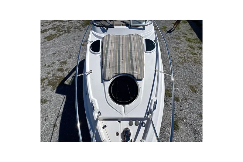 Slide: The Image of 2017 Regal 28 Express boat deck with sunpad and hatch, parked on gravel. - 58