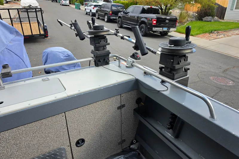 Slide: The Image of 2019 Raider 190 Explorer boat with fishing rod holders on a residential street. - 2