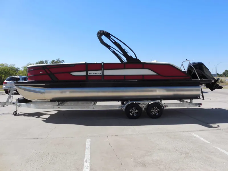 Slide: The Image of A modern pontoon boat with red and black design sits on a trailer in a parking lot. - 7