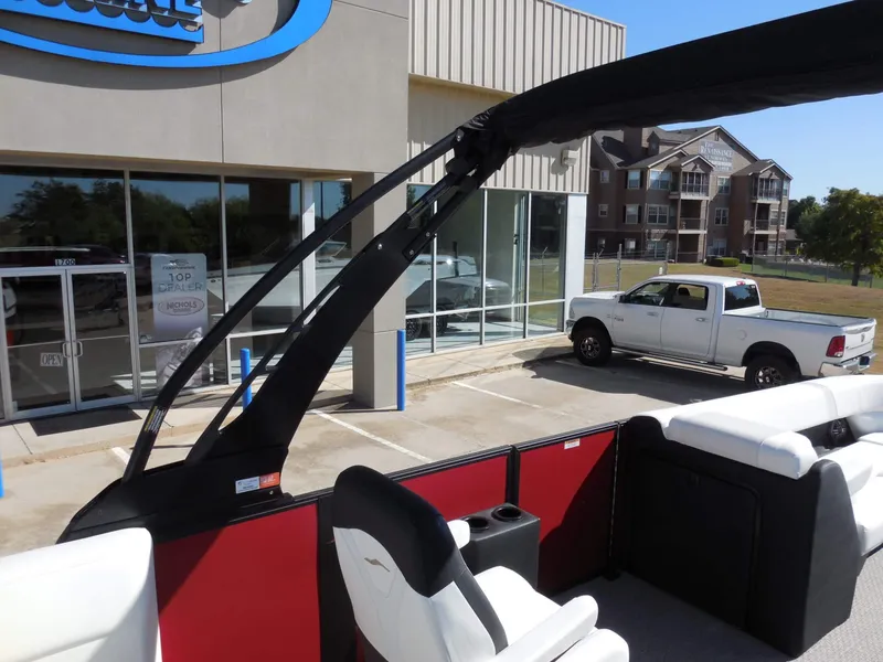 Slide: The Image of The image shows a modern boat with white seats and a black bimini top, located in a showroom. - 25