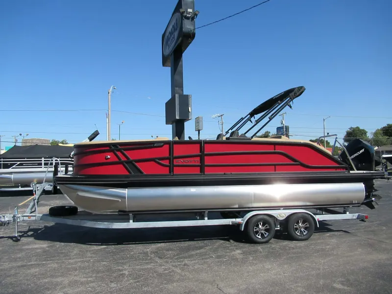 Slide: The Image of A red Evotti 521CS pontoon boat from 2027 sits on a trailer in a parking lot. - 2