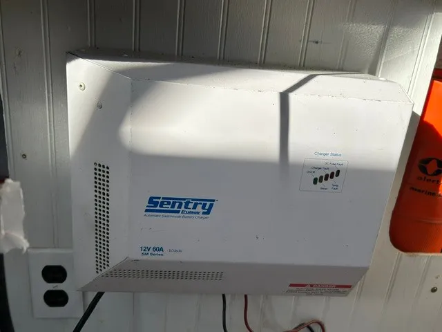 Slide: The Image of A Sentry battery charger is mounted on a wall. It features a charge status indicator. - 12