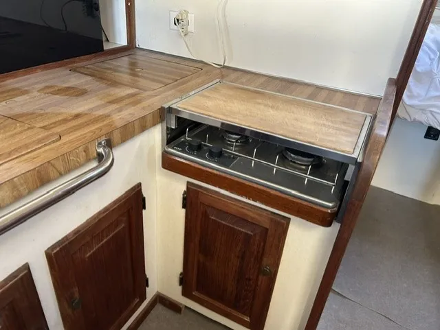 Slide: The Image of The galley of a 1979 Mainship 34 Trawler with wooden countertops and a built-in stove. - 16