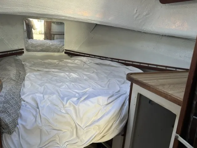 Slide: The Image of The cabin of a 1979 Mainship 34 Trawler with a cozy bed and a small mirror. - 21