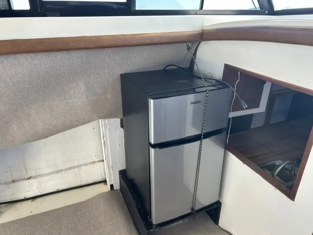 Slide: The Image of A small refrigerator is installed in the corner of a boat, surrounded by carpeted flooring. - 9