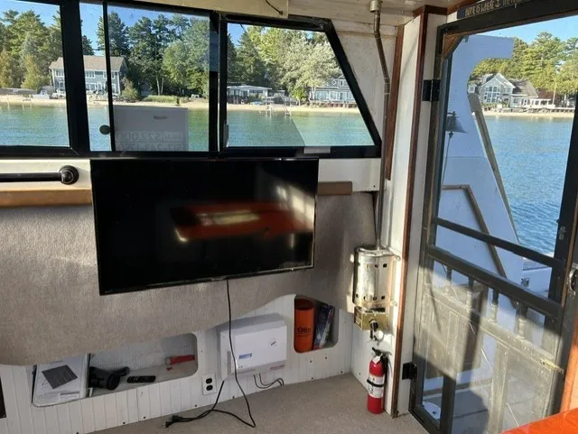 Slide: The Image of Interior of a 1979 Mainship 34 Trawler with a TV, fire extinguisher, and view of the water. - 10
