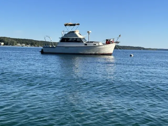 Slide: The Image of A 1979 Mainship 34 Trawler sits calmly on the water, surrounded by scenic landscape. - 1