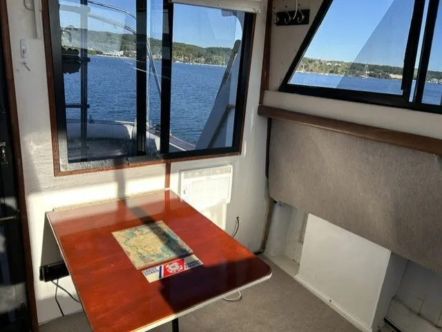 Slide: The Image of Interior of a 1979 Mainship 34 Trawler with a wooden table and windows overlooking the water. - 8