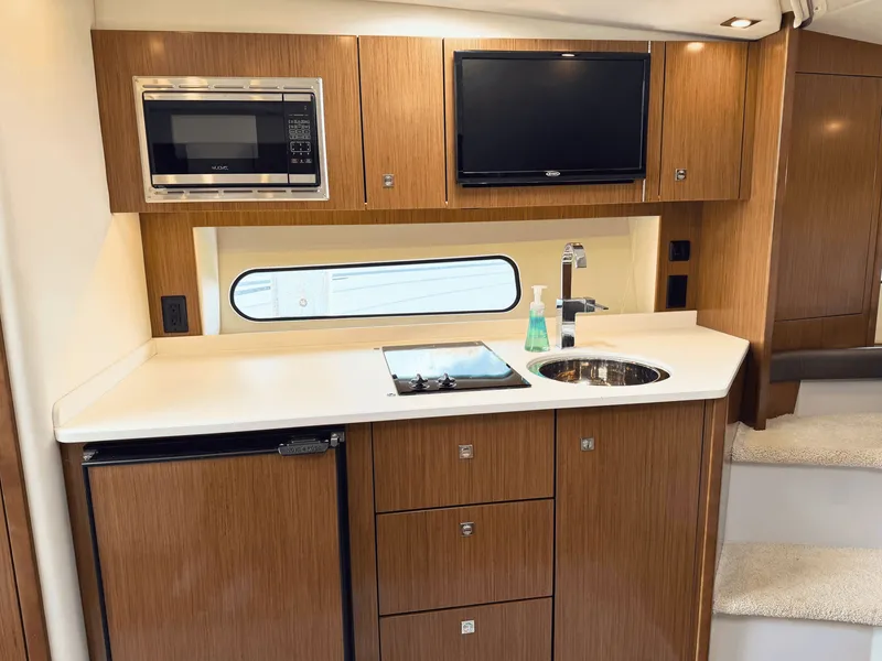 Slide: The Image of The yacht's galley features a microwave, stove, sink, and fridge in sleek wood cabinetry. - 17