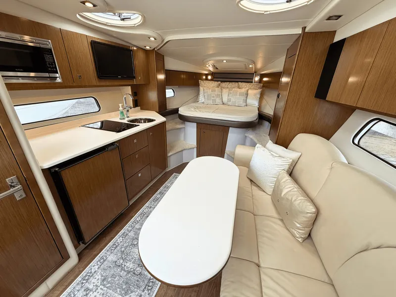 Slide: The Image of Interior of a 2018 Cruisers Yachts 35 Express with sleek kitchen, cozy sofa, and sleeping area. - 15