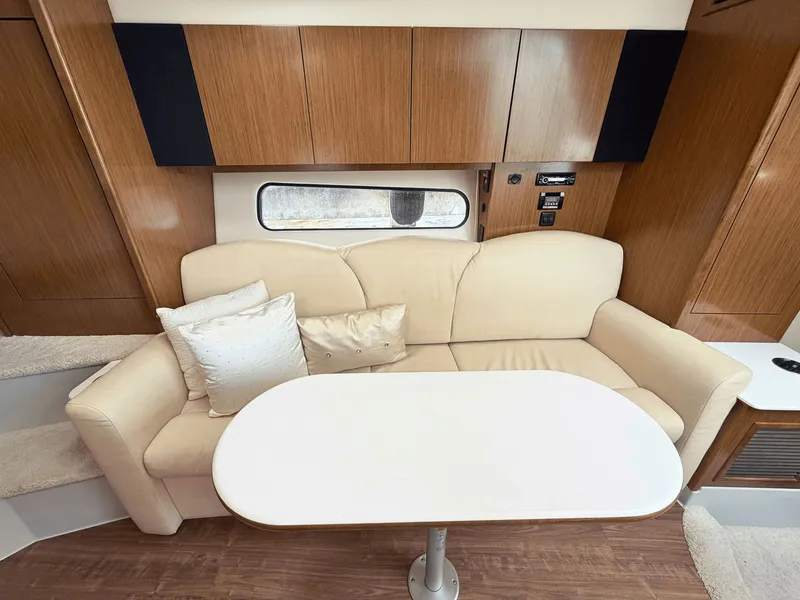 Slide: The Image of Interior of a 2018 Cruisers Yachts 35 Express with beige sofa and table. - 16
