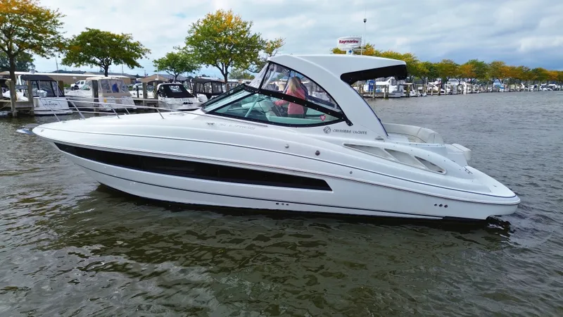 Slide: The Image of A white 2018 Cruisers Yachts 35 Express on calm water, surrounded by trees. - 1