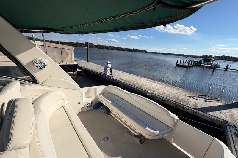 Slide: The Image of 2002 Sea Ray 340 Sundancer yacht docked by a serene waterfront under a clear blue sky. - 20