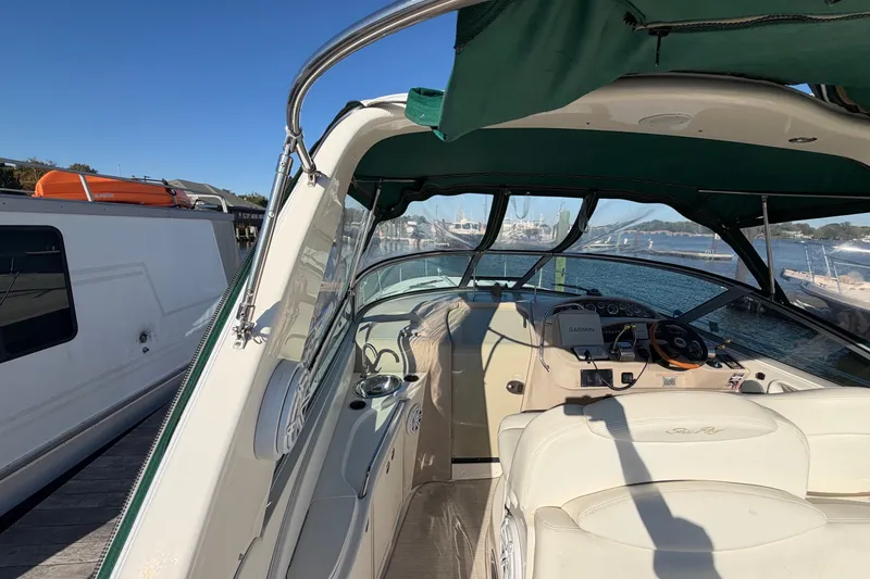 Slide: The Image of 2002 Sea Ray 340 Sundancer boat interior with helm, docked by the water. - 23
