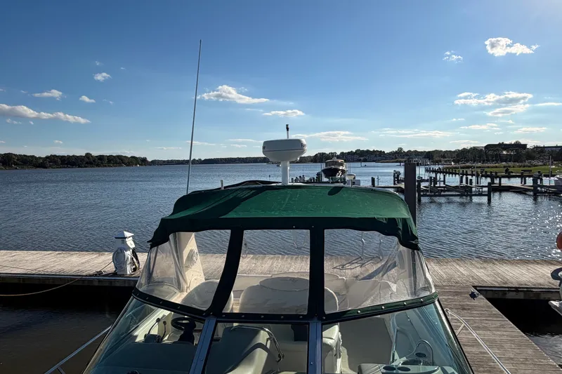 Slide: The Image of 2002 Sea Ray 340 Sundancer docked at a scenic marina under a clear blue sky. - 8