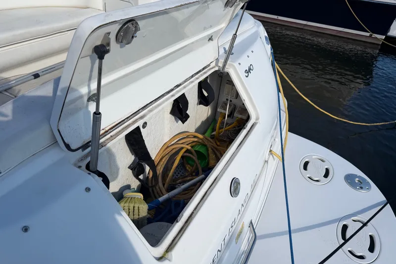 Slide: The Image of Open storage compartment on a 2002 Sea Ray 340 Sundancer boat, docked by the water. - 11