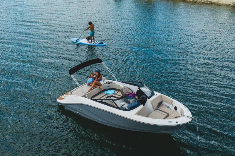 Slide: The Image of Manufacturer Provided Image: 2025 Bayliner V20i boat on water with paddleboarder nearby. - 2